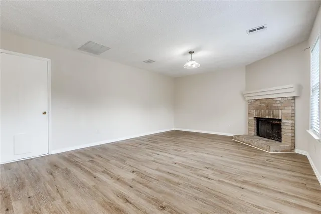 a view of empty room with wooden floor and fireplace