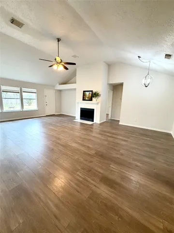 an empty room with wooden floor chandelier fan and windows