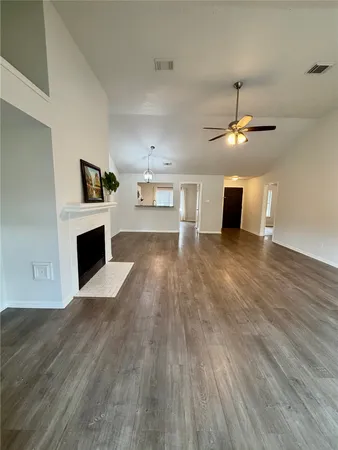 a view of a livingroom with a fireplace a ceiling fan and wooden floor
