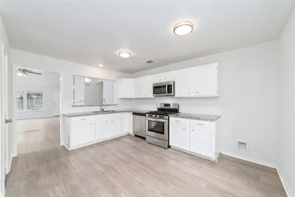 a large white kitchen with stainless steel appliances granite countertop a stove and a sink