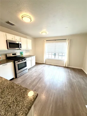 a kitchen with stainless steel appliances granite countertop a stove a sink and a microwave