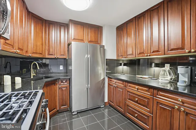 a kitchen with granite countertop a refrigerator stove and cabinets