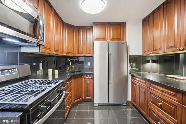 a kitchen with granite countertop a refrigerator and a stove top oven