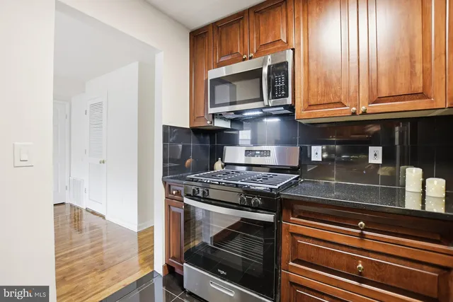 a kitchen with granite countertop a stove top oven microwave and cabinets