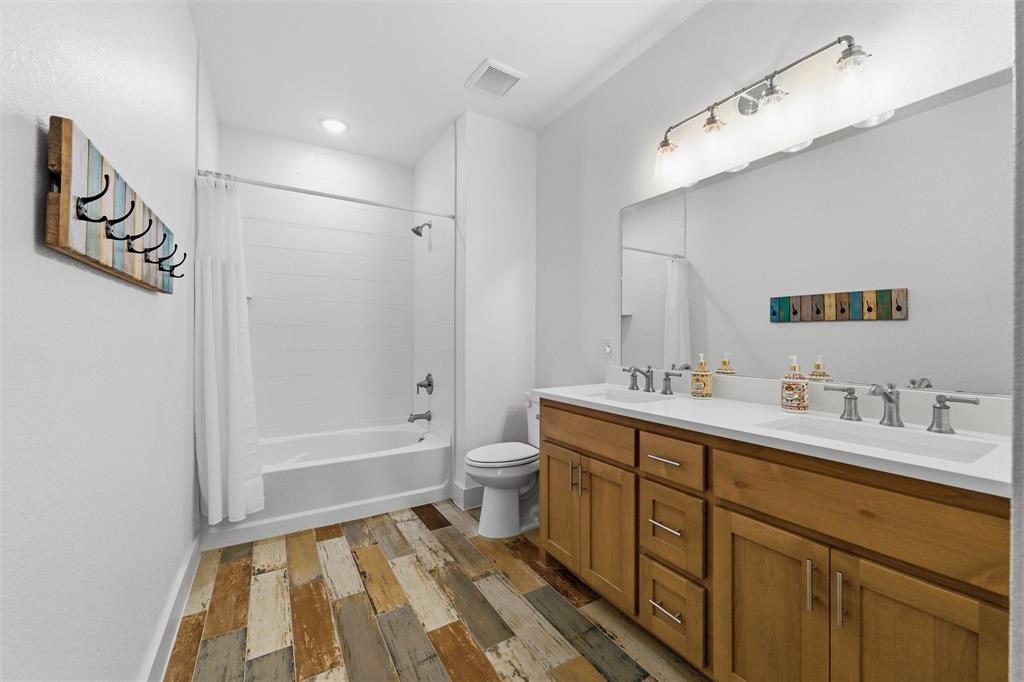 6625 Sandy Beach Road Azle, TX 76020 - Photo 23 of 40 Secondary bathroom features dual sinks with extended vanity space, tub and shower combination with tiled surround, decorative flooring detail, and neutral finishes throughout.