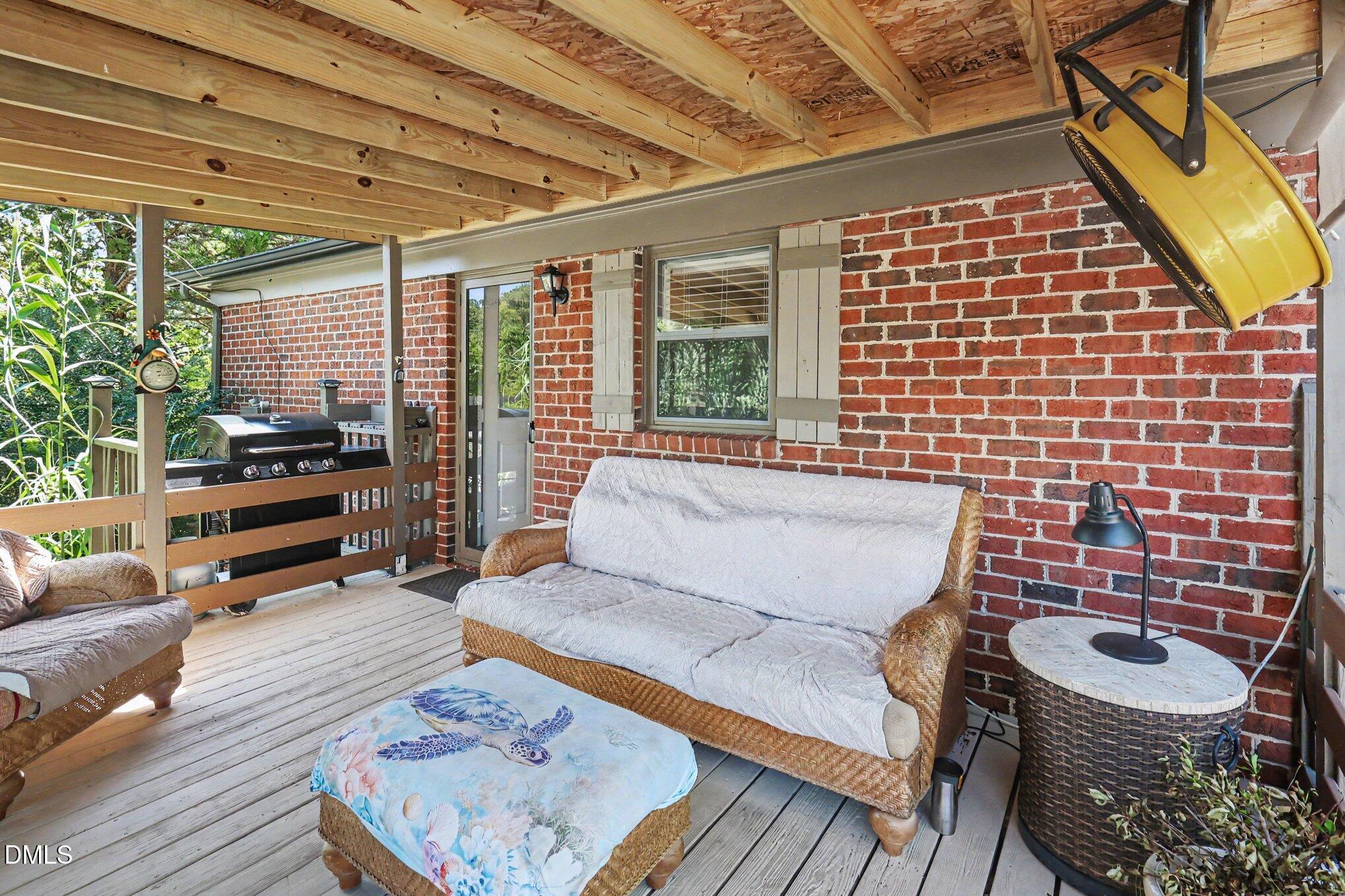 5817 Mitchell Mill Road Wake Forest, NC 27587 - Photo 24 of 34 Covered outdoor deck with exposed wood ceiling beams, wood-plank flooring, and brick exterior wall