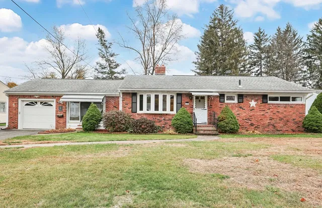 a front view of a house with a garden and trees