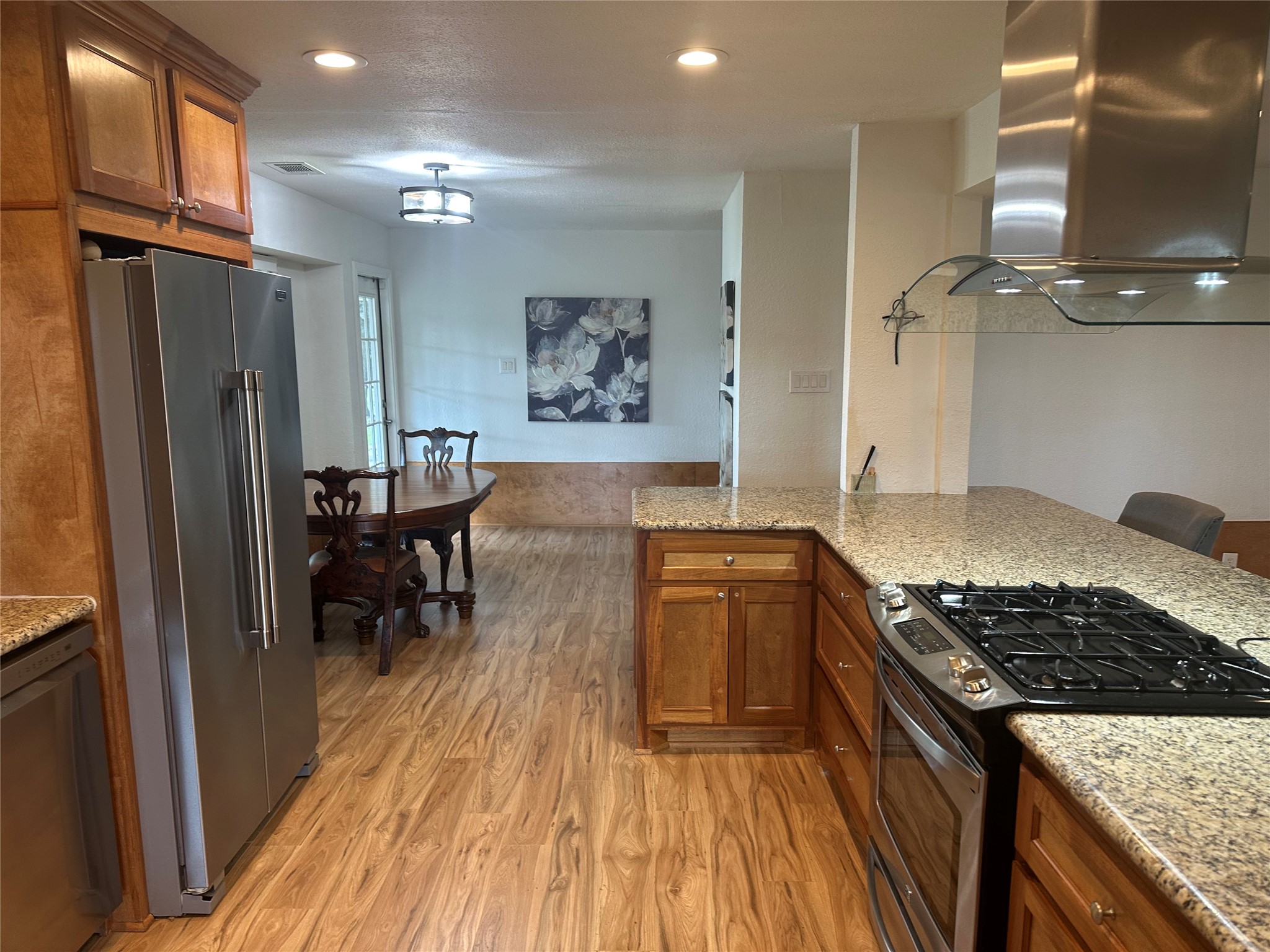 16607 Mueschke Road Cypress, TX 77433 - Photo 24 of 24 a kitchen with stainless steel appliances granite countertop a stove top oven a refrigerator and a dining table with wooden floor