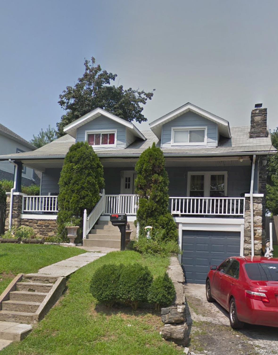 Bungalow-style home with a porch, a chimney, driveway, a garage, and stone siding