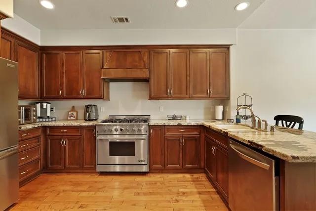 a kitchen with stainless steel appliances granite countertop a stove a sink dishwasher and a refrigerator