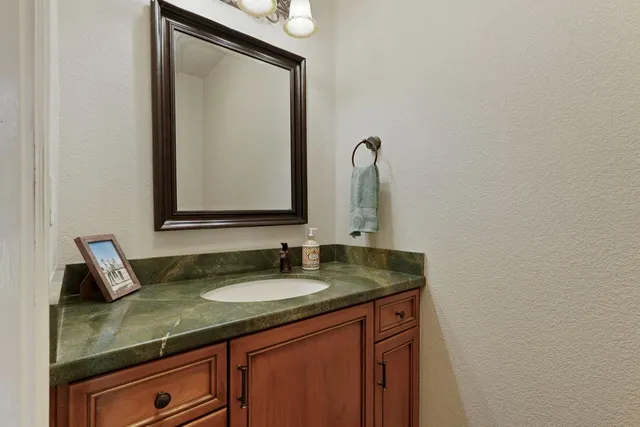 a bathroom with a granite countertop sink and a mirror