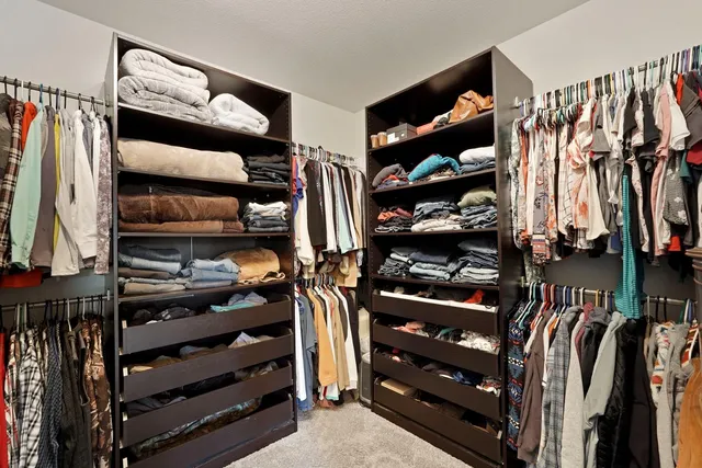 a view of walk in closet with clothes and shoes
