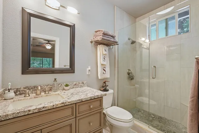 a bathroom with a granite countertop sink a toilet and a mirror