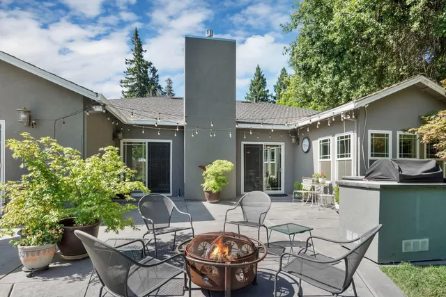 a view of a patio with table and chairs potted plants and large tree