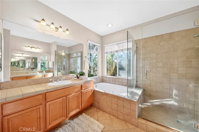 a bathroom with a granite countertop bathtub shower sink mirror and toilet
