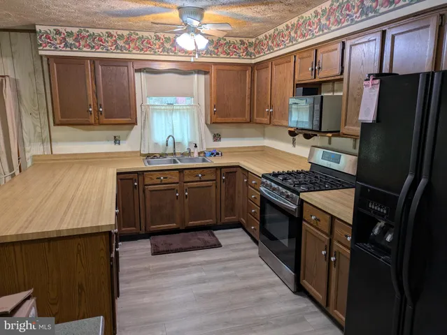 a kitchen with stainless steel appliances granite countertop a stove a sink dishwasher a refrigerator and a oven with wooden floor