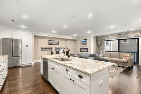 a large white kitchen with stainless steel appliances granite countertop a lot of counter space and wooden floor