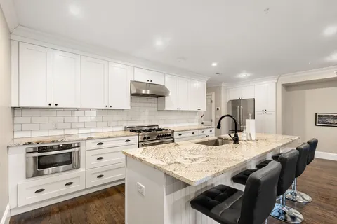 a kitchen with granite countertop a sink a stove and cabinets