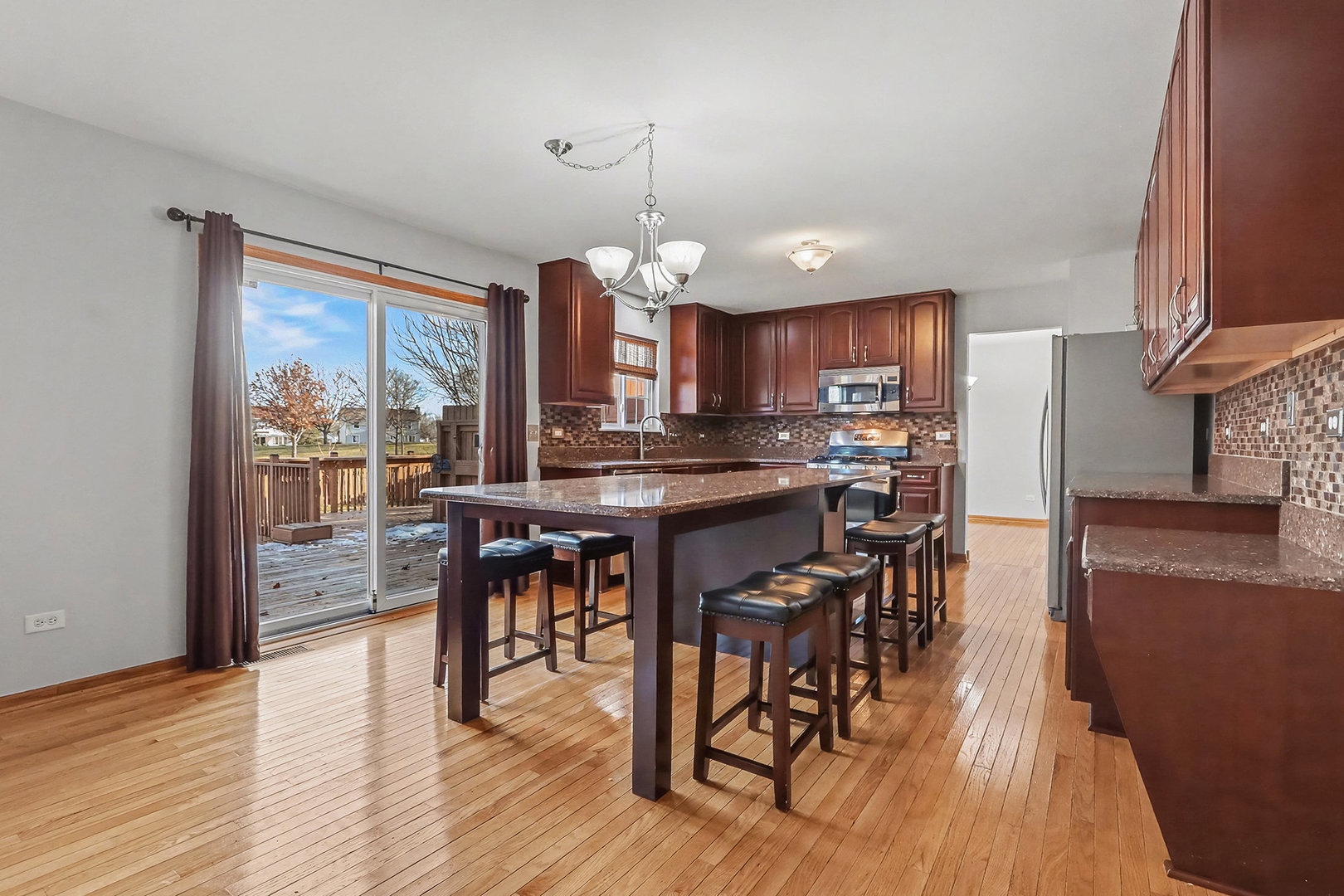 1576 Marigold Lane Minooka, IL 60447 - Photo 6 of 25 a kitchen with stainless steel appliances granite countertop wooden floor a dining table and chairs