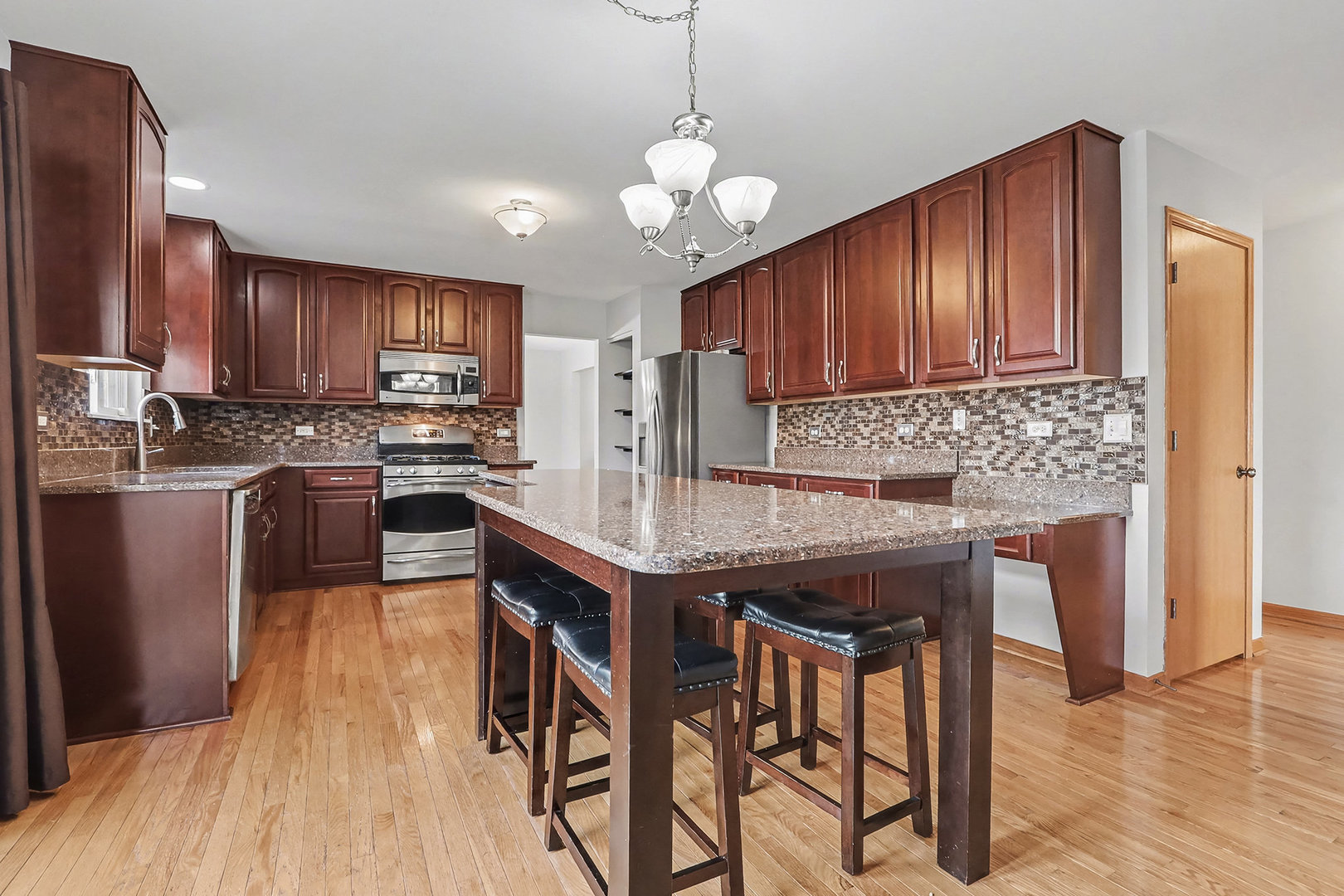1576 Marigold Lane Minooka, IL 60447 - Photo 8 of 25 a kitchen with kitchen island granite countertop wooden floors and wooden cabinets