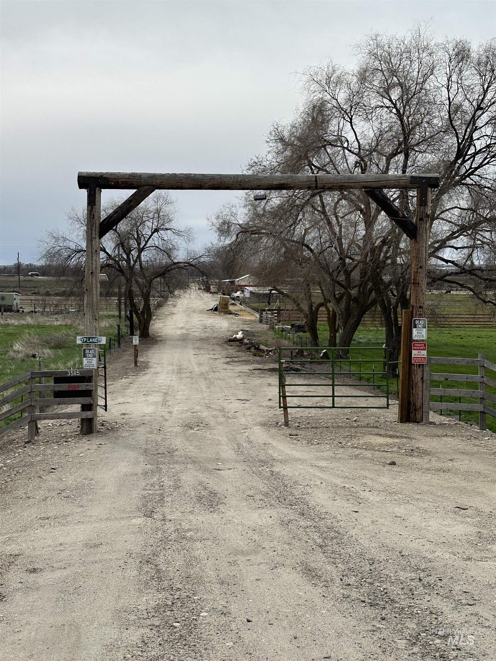 View of dirt / gravel driveway with a view of rural / pastoral area, a gate, and a gated entry