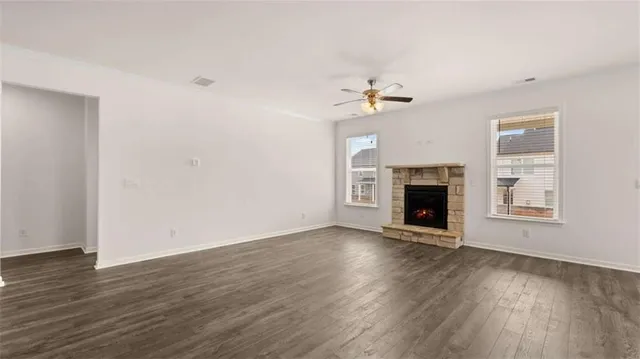 a view of an empty room with window and kitchen view