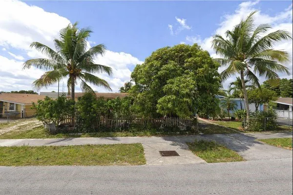 a palm tree sitting in front of a house with a garden