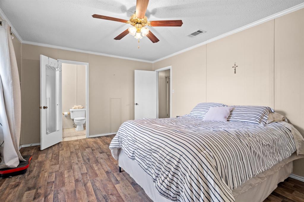 101 Taylor Street Como, TX 75431 - Photo 17 of 39 a bedroom with a large bed and a chandelier