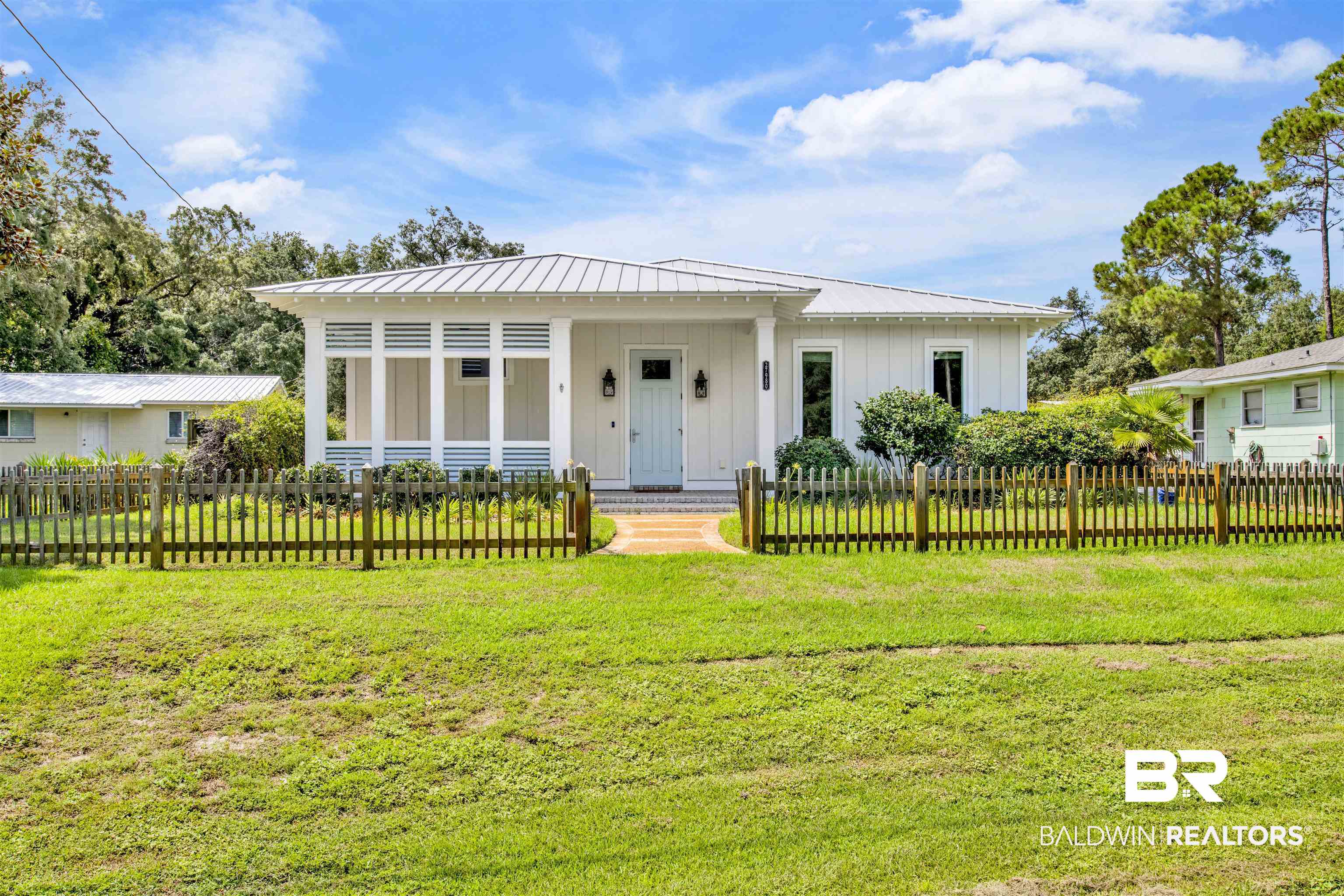 27980 Canal Road Orange Beach, AL 36561 - Photo 1 of 46 View of front of home featuring board and batten siding, a metal roof, a fenced front yard, and a standing seam roof
