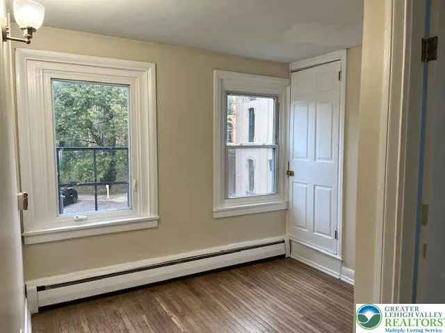 a view of an empty room with wooden floor and a bathroom