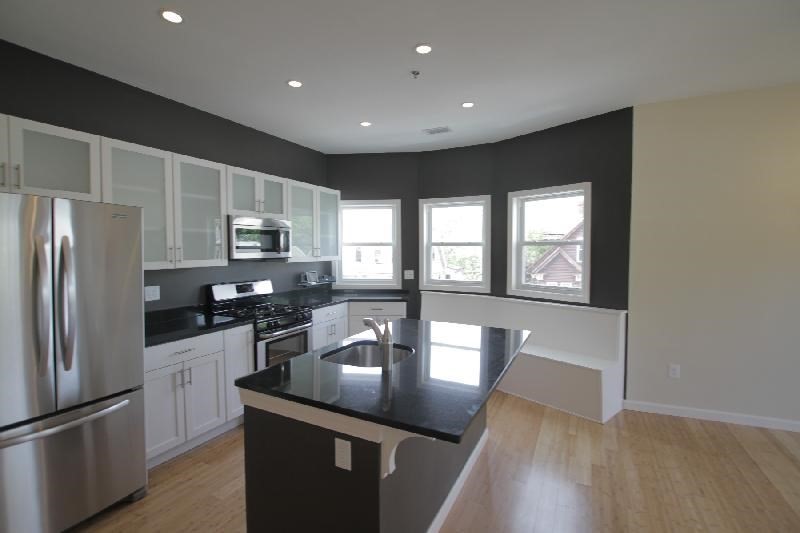 a kitchen with stainless steel appliances granite countertop a refrigerator a stove a sink a microwave and island