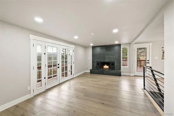 an empty room with wooden floor fireplace and windows