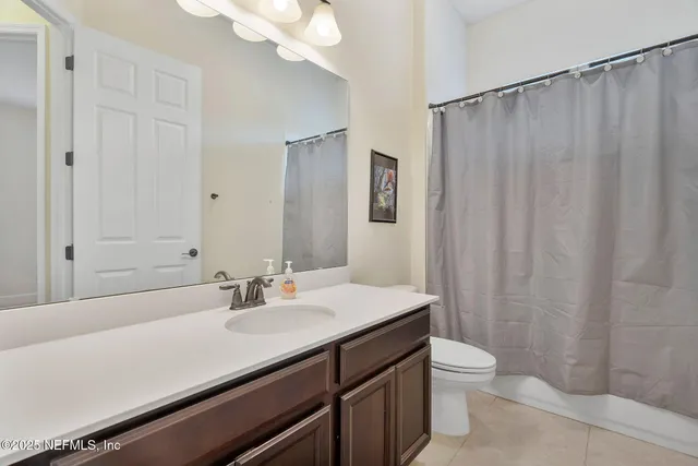 a bathroom with a sink a toilet a mirror and shower curtain