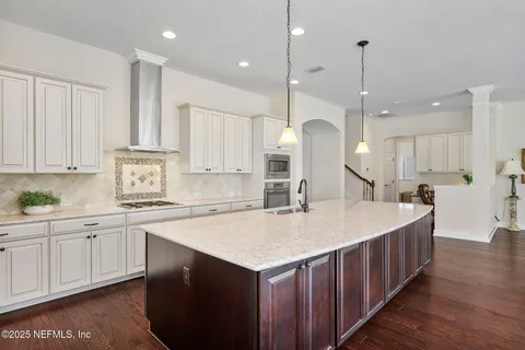 a kitchen with stainless steel appliances kitchen island wooden floors wooden cabinets and entryway