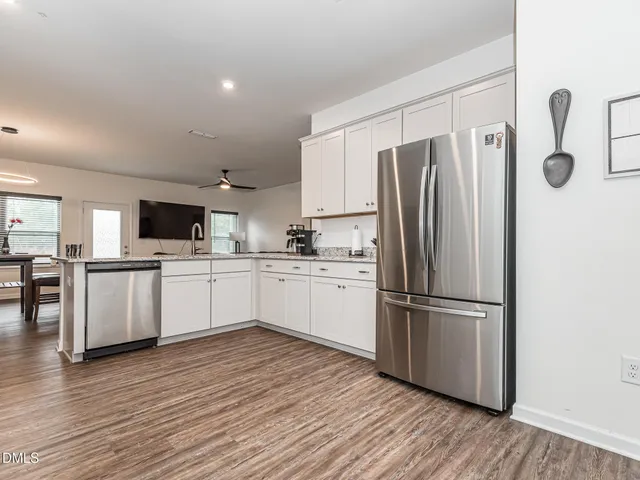 a kitchen with white cabinets stainless steel appliances and wooden floor
