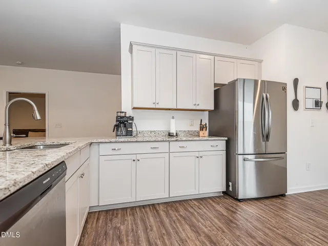 a kitchen with granite countertop cabinets stainless steel appliances a sink and wooden floor
