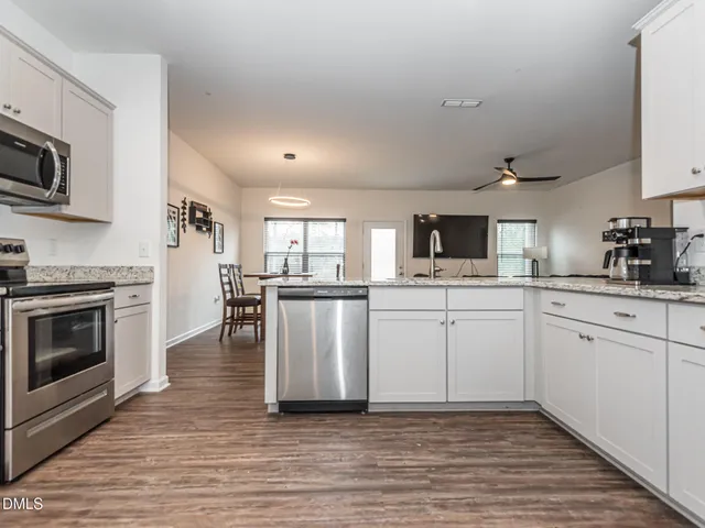 a kitchen with cabinets stainless steel appliances and wooden floor