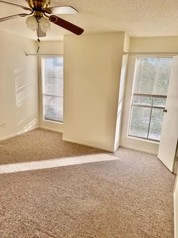 an empty room with windows and fan