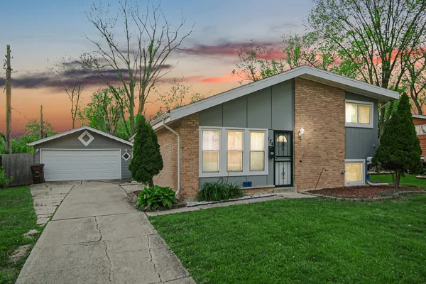 a front view of a house with a garden and trees