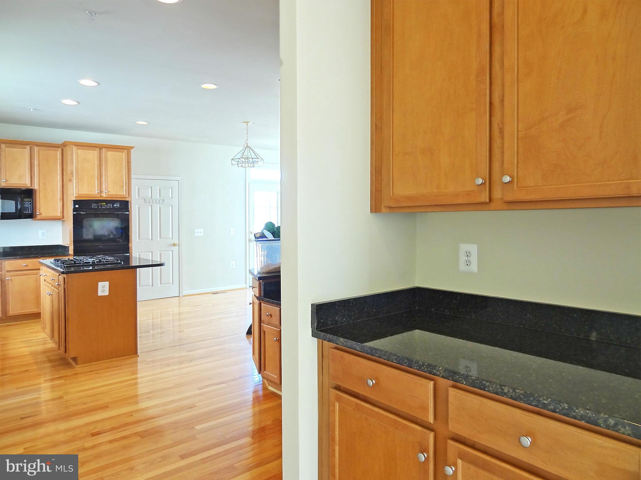 9800 Traver Street Bowie, MD 20721 - Photo 12 of 30 a kitchen with granite countertop a sink a stove and cabinets