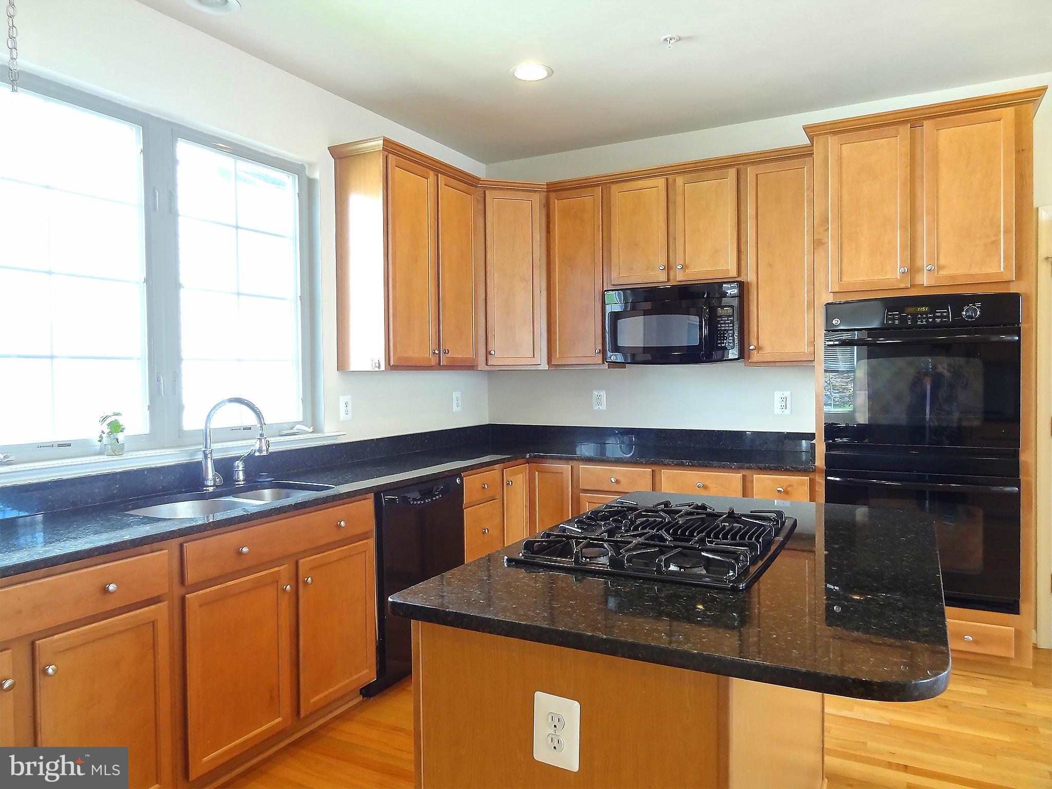 9800 Traver Street Bowie, MD 20721 - Photo 14 of 30 a kitchen with wooden cabinets and a stove top oven