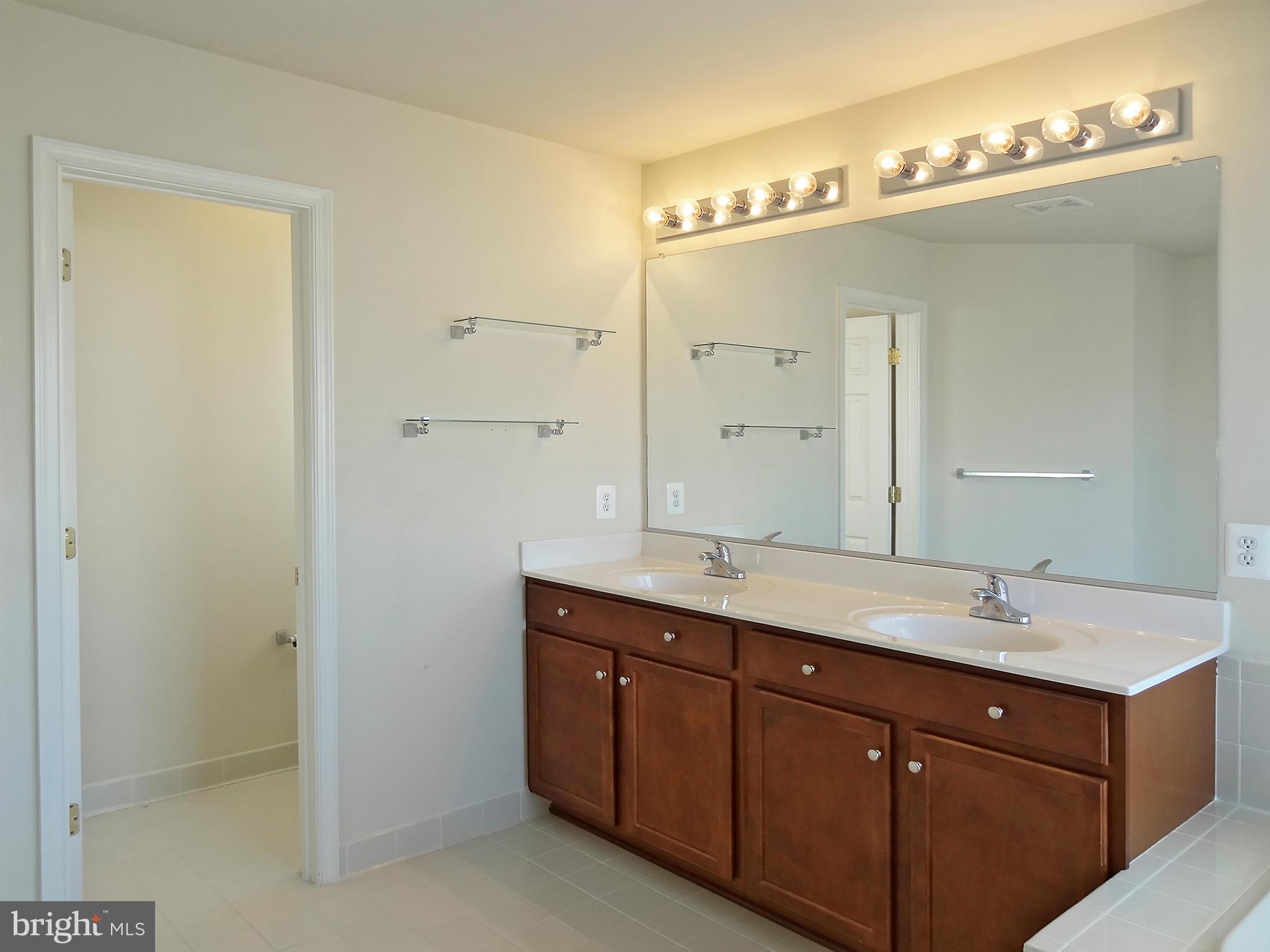 9800 Traver Street Bowie, MD 20721 - Photo 22 of 30 a bathroom with a double vanity sink and mirror