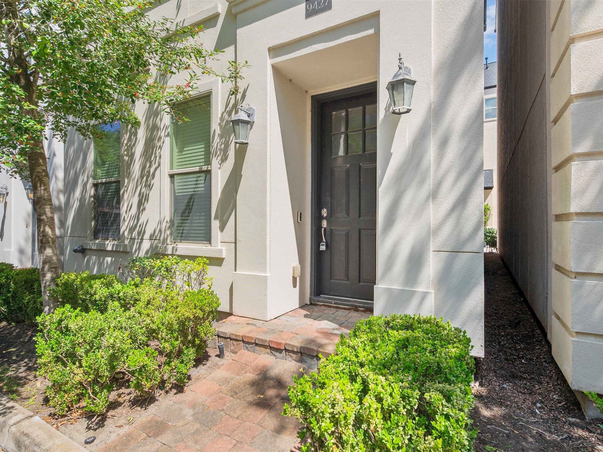 9427 London Bridge Station Houston, TX 77045 - Photo 3 of 30 Welcome to your new home: a charming front entrance framed by lush greenery and elegant lanterns, inviting you into a world of comfort and style.