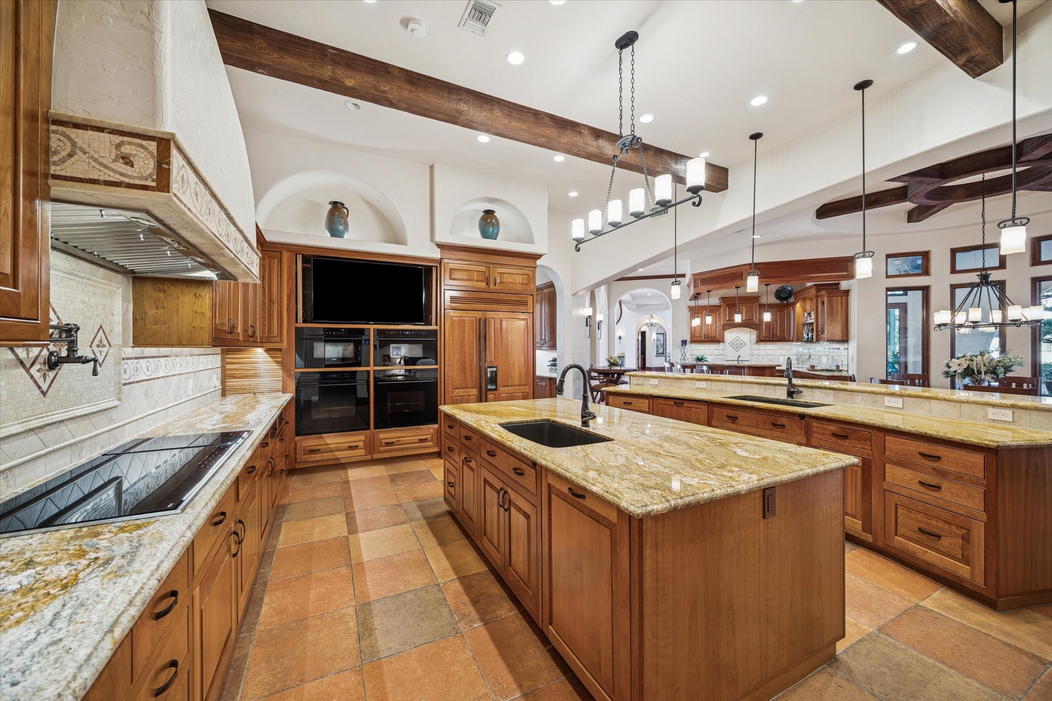 21538 Mueschke Road Tomball, TX 77377 - Photo 14 of 50 Elegant and inviting kitchen space. This stunning kitchen features double Wolf convection and conventional ovens, making it perfect for entertaining loved ones while cooking and spending quality family time during holidays. Designed for both style and function, it includes energy-efficient LED lighting, beautiful wood-beam ceilings, and a spacious island with a breakfast bar that opens to the family room — perfect for gathering with friends while cooking or enjoying casual conversations.