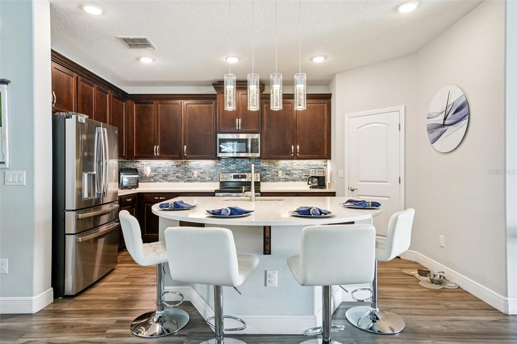 12627 Vander Way New Port Richey, FL 34654 - Photo 18 of 77 a kitchen with stainless steel appliances granite countertop a dining table chairs refrigerator and sink