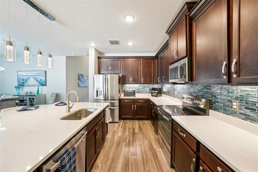 12627 Vander Way New Port Richey, FL 34654 - Photo 22 of 77 a kitchen with stainless steel appliances granite countertop sink stove refrigerator and cabinets