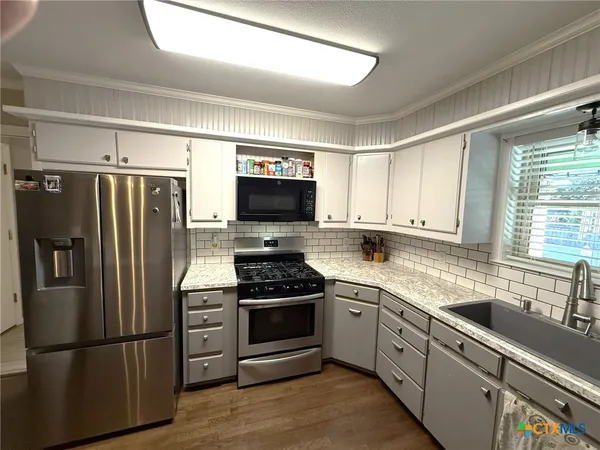 a kitchen with granite countertop a sink a window and cabinets