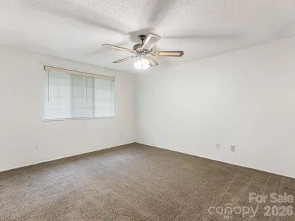 an empty room with windows and fan