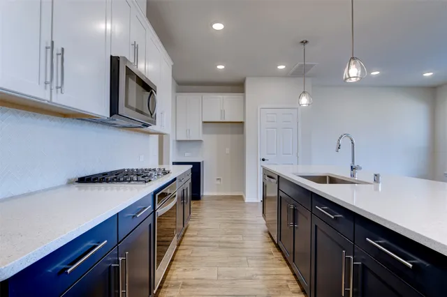 a kitchen with stainless steel appliances granite countertop a sink a stove and a refrigerator