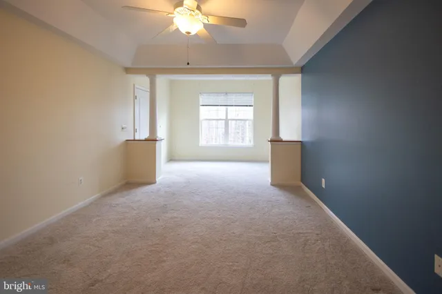 en empty room with windows and chandelier fan